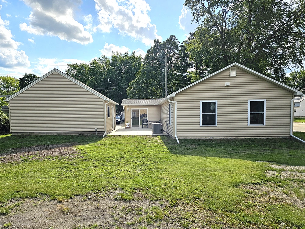 East side exterior view of the yard, house, private patio, and 2-stall garage